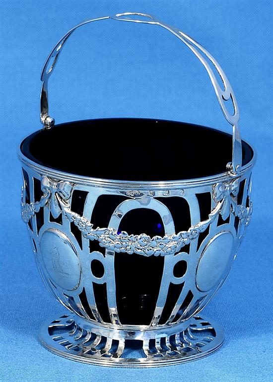 An Edwardian pierced silver sugar basket and blue glass liner, Height to handle 6”/155mm Dia 104mm Weight Silver only: 5.1oz/145grms